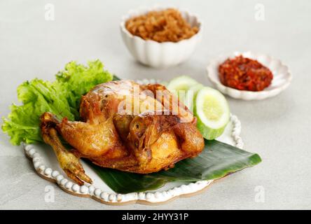 Ayam Goreng Utuh. Poulet entier frits servi avec de la pâte de Chili Sambal et des légumes frais Banque D'Images