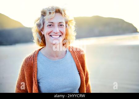 Jeune femme blanche mûre blonde en plein air sur une plage par temps ensoleillé. Plage de Berria, Cantabrie, Espagne, Europe. Banque D'Images