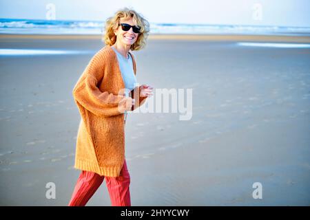 Jeune femme blanche mûre blonde en plein air sur une plage par temps ensoleillé. Plage de Berria, Cantabrie, Espagne, Europe. Banque D'Images