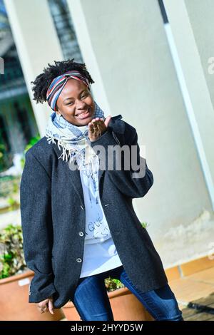 Jeune femme africaine avec un style de cheveux frais et un t-shirt posant à l'extérieur. Banque D'Images