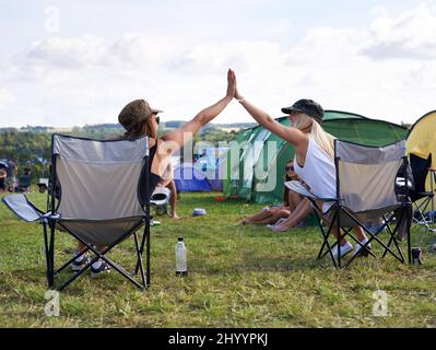 Joyeux campeurs. Photo de deux amis en vue de leur donner un cinq haut lors d'un festival en plein air. Banque D'Images