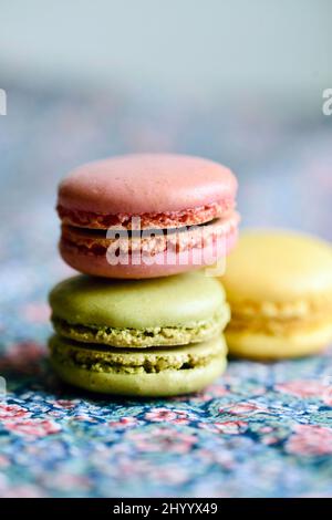 trois macarons français sur une nappe fleurie à la lumière naturelle Banque D'Images