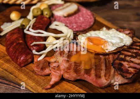 Différentes sortes de saucisses grillées avec des œufs. Une sélection de viandes gastronomiques grillées sur une planche de bois rustique. Saucisses grillées avec du pain maison. Banque D'Images