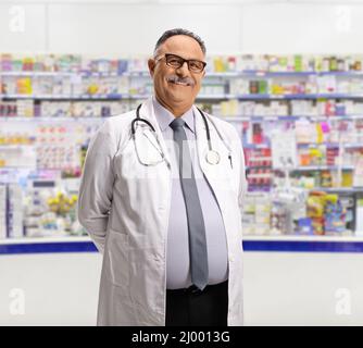 Pharmacien de sexe masculin mature devant un comptoir de pharmacie souriant à la caméra Banque D'Images