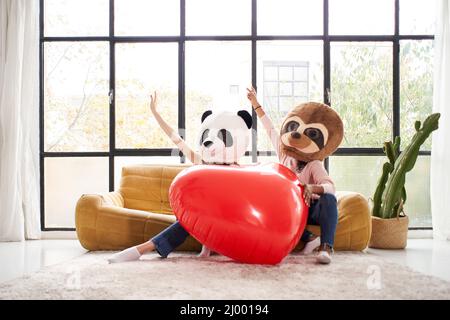 Drôles femmes portant le masque d'animal porter panda tenant le grand coeur à la maison - heureux positif émotions les gens ensemble dans l'amour Banque D'Images
