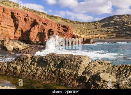 La plage d'El Golfo à Lanzarote en regardant vers les falaises qui surplombent la lagune verte (Charco de los Clicos) Banque D'Images