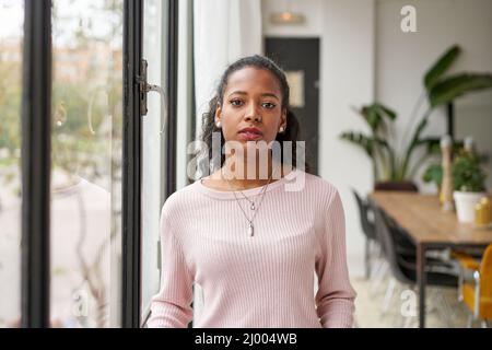 Confiante femme africaine professionnelle avec un visage sérieux debout à la maison dans le bureau regardant la caméra. Femme entrepreneur confiante posant Banque D'Images