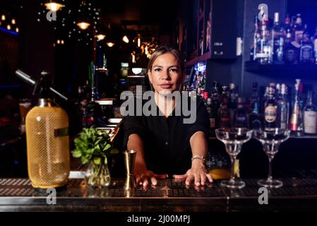 Latina prépare un cocktail à un comptoir de bar. Métier de serveuse d'emploi Banque D'Images