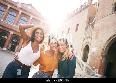 Trois amies joyeuses qui s'amusent en plein air en vacances d'été en ville. Portrait d'une femme souriante qui se serre en regardant l'appareil photo ensemble Banque D'Images