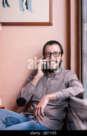 Jeune homme caucasien souriant heureux de parler sur le smartphone Banque D'Images