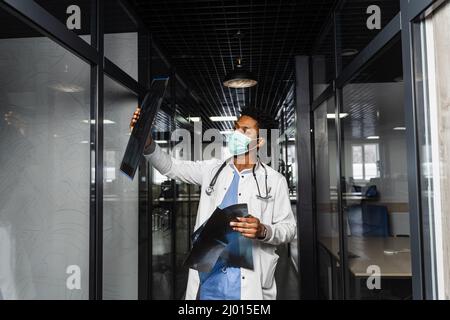 Médecin africain avec radiographie en clinique médicale. Étudiant en médecine noire dans l'étude de masque médical à l'université Banque D'Images