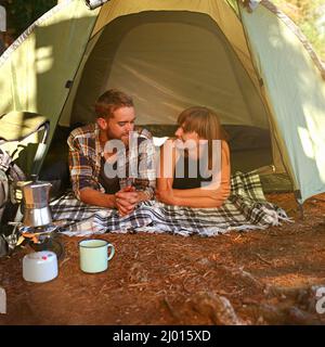 Dans les bois.Photo d'un jeune couple allongé dans une tente en regardant vers l'extérieur. Banque D'Images