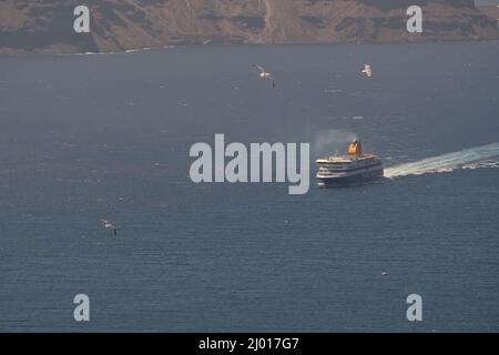 Santorini, Grèce - 10 mai 2021 - Un ferry qui s'approche du port d'Athinios à Santorin et des mouettes qui volent Banque D'Images