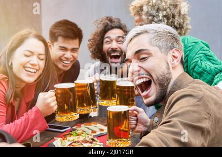 Des amis heureux prenant un selfie au restaurant de la terrasse pour boire des bières Banque D'Images