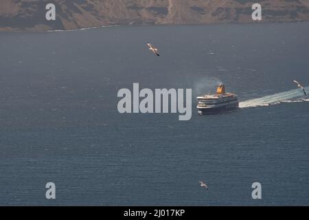 Santorini, Grèce - 10 mai 2021 - Un ferry qui s'approche du port d'Athinios à Santorin et des mouettes qui volent Banque D'Images