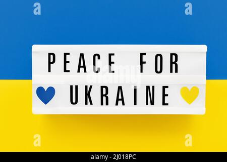 PEACE FOR UKRAINE écrit dans une visionneuse sur le drapeau ukrainien couleurs fond. Vue de dessus Banque D'Images