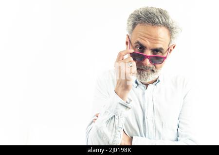 Homme d'âge moyen caucasien regardant de manière suspecte l'appareil photo tenant des lunettes de soleil portrait isolé blanc arrière-plan studio tourné . Photo de haute qualité Banque D'Images