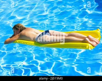 Femme d'âge mûr caucasienne couché sur un matelas gonflable jaune pour bronzer une piscine Banque D'Images