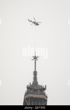 Paris, France. 15th mars 2022. Un hélicoptère lève une nouvelle antenne au sommet de la Tour Eiffel à Paris, en France, le 15 mars 2022. La Tour Eiffel a grandi de six mètres mardi après l'installation d'une nouvelle antenne radio sur le monument de Paris, à une hauteur de 330 mètres. Crédit: Florent Michel/Xinhua/Alay Live News Banque D'Images