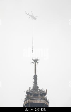 Paris, France. 15th mars 2022. Un hélicoptère lève une nouvelle antenne au sommet de la Tour Eiffel à Paris, en France, le 15 mars 2022. La Tour Eiffel a grandi de six mètres mardi après l'installation d'une nouvelle antenne radio sur le monument de Paris, à une hauteur de 330 mètres. Crédit: Florent Michel/Xinhua/Alay Live News Banque D'Images