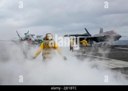 Mer des Philippines, États-Unis. 09 février 2022. Les marins de la Marine américaine préparent un avion de chasse F/A-18E Super Hornet et un avion de chasse furtif F-35C Lightning II de l'USMC pour le lancement à partir du pont de vol du porte-avions USS Abraham Lincoln de la classe Nimitz lors des opérations de routine, le 9 mars 2022 en mer des Philippines. Crédit : MC3 Michael Singley/Planetpix/Alamy Live News Banque D'Images