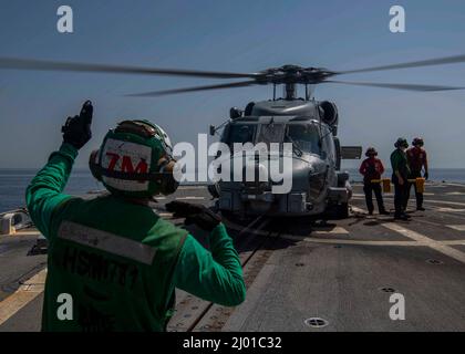 ARABIAN GULF (14 mars 2022) le mécanicien de structure aéronautique 3rd classe Nguyen Doan, à gauche, dirige un hélicoptère MH-60R Sea Hawk, attaché aux « Raptors » de l'Escadron de frappe maritime (HSM) 71 lors des opérations de vol à bord du destroyer de missiles guidés USS Gridley (DDG 101) dans le golfe Arabique, en mars 14. Gridley est déployé dans la zone d'opérations de la flotte américaine 5th à l'appui des opérations navales afin d'assurer la stabilité et la sécurité maritimes dans la région centrale, reliant la Méditerranée et le Pacifique par l'océan Indien occidental et trois points d'étranglement stratégiques. (É.-U. Bleu marine photo par Banque D'Images