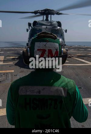 ARABIAN GULF (14 mars 2022) le mécanicien de charpente de l'aviation 3rd classe Nguyen Doan dirige un hélicoptère MH-60R Sea Hawk, attaché aux « Raptors » de l'Escadron de frappe maritime (HSM) 71 lors des opérations de vol à bord du destroyer de missiles guidés USS Gridley (DDG 101) dans le golfe Arabique, en mars 14. Gridley est déployé dans la zone d'opérations de la flotte américaine 5th à l'appui des opérations navales afin d'assurer la stabilité et la sécurité maritimes dans la région centrale, reliant la Méditerranée et le Pacifique par l'océan Indien occidental et trois points d'étranglement stratégiques. (É.-U. Photo de la marine par Mass Co Banque D'Images