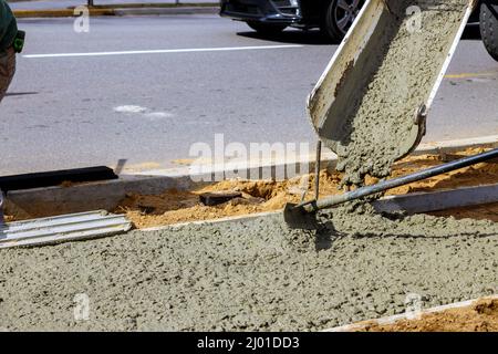 Les travailleurs de béton mélangeur avec verser le ciment pendant à résidentiel sur le trottoir Banque D'Images