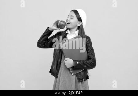 Heureux enfant d'âge scolaire profiter de manger savoureux bio vitamine pomme jaune fond, nourriture saine Banque D'Images