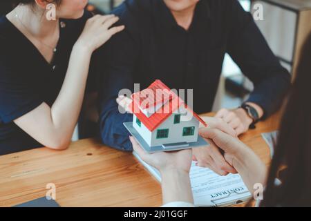 Le jeune couple décide avant de signer le contrat et le prix tandis que le courtier offre le prix exclusif. Concept immobilier. Banque D'Images