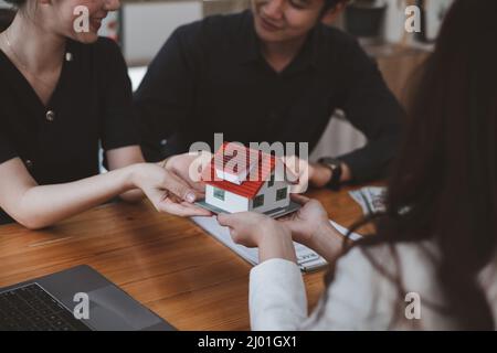 Le jeune couple décide avant de signer le contrat et le prix tandis que le courtier offre le prix exclusif. Concept immobilier. Banque D'Images