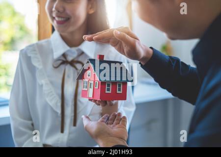 Le jeune couple décide avant de signer le contrat et le prix tandis que le courtier offre le prix exclusif. Concept immobilier. Banque D'Images