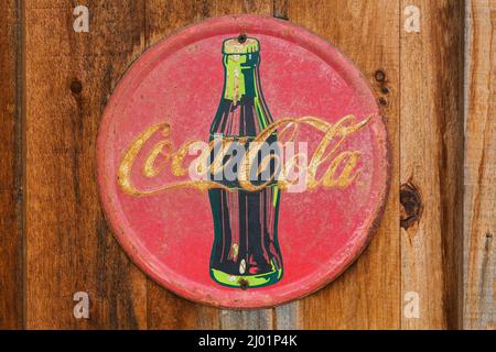 Vintage Coca Cola Soft Drink Company rond métal publicité affiche sur le mur rustique de bois de planche. Banque D'Images