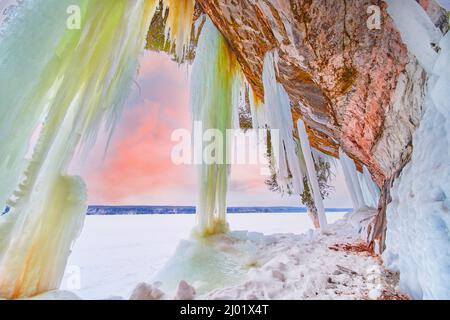 Le lever du soleil d'hiver brille sur un lac gelé avec de grandes glaces bleues et vertes provenant de rochers Banque D'Images