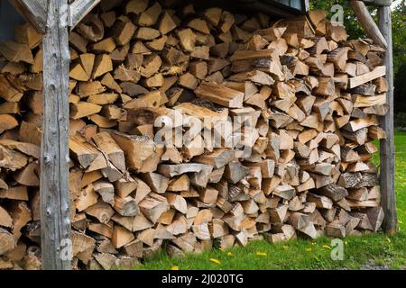 Bois de chauffage empilé stocké dans un abri en bois à conception ouverte. Banque D'Images