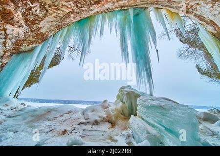De gros morceaux de glaçons cassés à l'entrée de la grotte de glace avec des glaçons bleus suspendus Banque D'Images