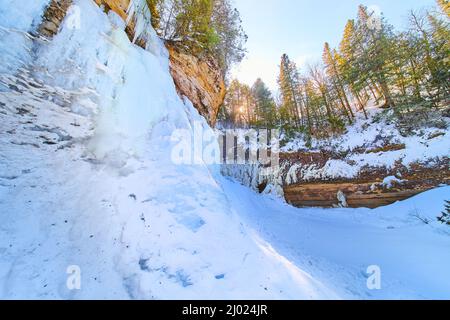 Glace et neige d'une cascade gelée sur des falaises avec des arbres Banque D'Images