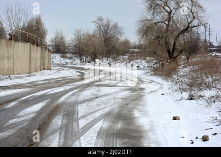 Pistes de roues de voiture, passant des voitures sur une route enneigée et en fonte d'hiver, un fond intéressant. Banque D'Images