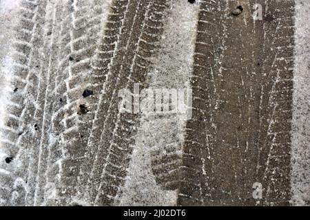 Pistes de roues de voiture, passant des voitures sur une route enneigée et en fonte d'hiver, un fond intéressant. Banque D'Images
