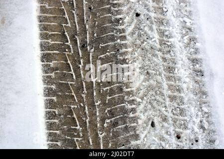 Pistes de roues de voiture, passant des voitures sur une route enneigée et en fonte d'hiver, un fond intéressant. Banque D'Images