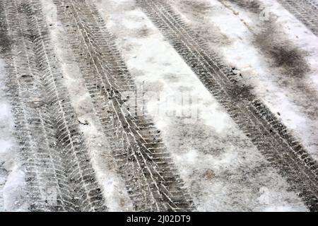 Pistes de roues de voiture, passant des voitures sur une route enneigée et en fonte d'hiver, un fond intéressant. Banque D'Images