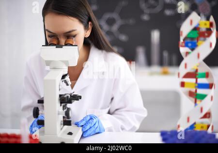 La prochaine étape de l'évolution humaine. Profil d'une scientifique féminine regardant un échantillon au microscope. Banque D'Images