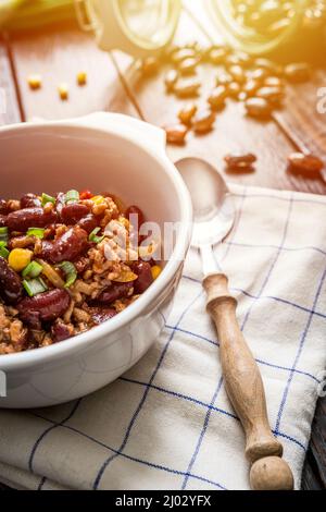 Chili mexicain ou Chili con carne. Haricots rouges cuits, viande hachée, piment, maïs et poivre dans une casserole sur une table en bois Banque D'Images