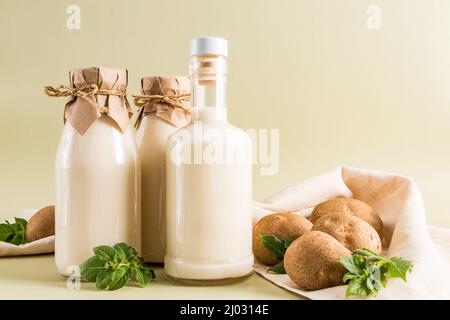 Délicieux lait de pomme de terre sain dans des bouteilles de verre sur fond beige pastel. Angle étroit. Source de fer, vitamine C Banque D'Images