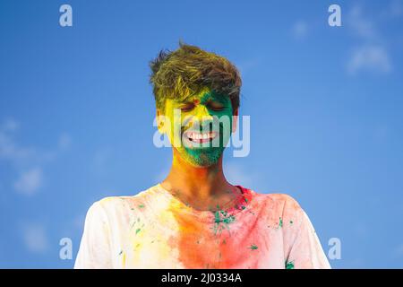 Portrait d'un jeune homme indien recouvert de holi jaune et vert Banque D'Images