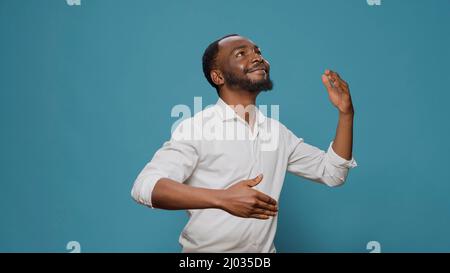 Homme du millénaire faisant de la danse robotique bouge sur la caméra, en s'amusant avec la fête disco contemporaine. Jeune homme insouciant se déplaçant comme robot, dansant sur la musique urbaine unique. Fête de Noël. Banque D'Images