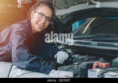 Le personnel mécanicien vérifie le concept de moteur de voiture. Femme intelligente et forte travaillant dans un garage de voiture. Banque D'Images