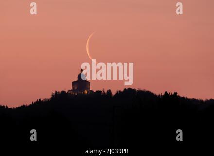 Le croissant de lune s'amenuise au lever du soleil au-dessus du sanctuaire de San Luca, Bologne, Émilie-Romagne, Italie, Europe Banque D'Images