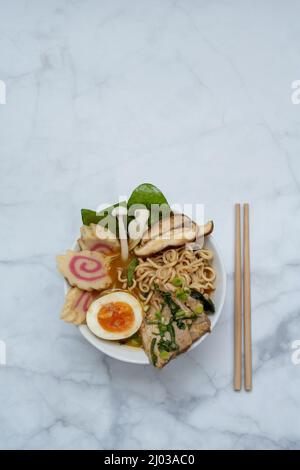 Bol à soupe de ramen avec baguettes sur table en marbre Banque D'Images