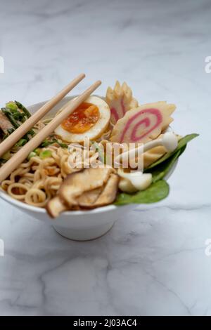 Bol à soupe de ramen avec baguettes sur table en marbre Banque D'Images